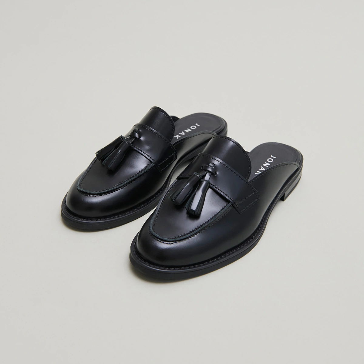 Loafers with tassels and open backs in black glazed leather | NATALY