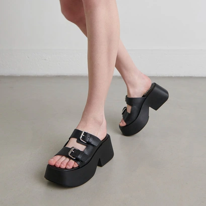 Mules with thick straps, buckles and open toes in black grained leather | ENOLA